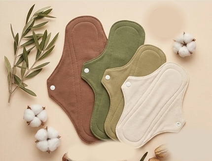 Flat-lay ürün fotoğrafı — kumaş pedler, pamuk çiçekleri, zeytin dalı